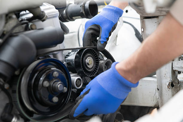 a person with blue gloved shown removing the timing belt from a vehicle